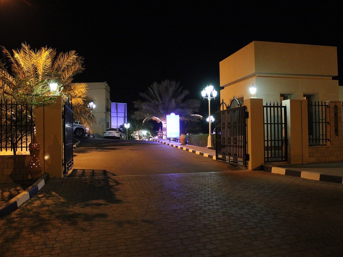 Palm-lined resort entrance illuminated at night in Khasab, Oman
