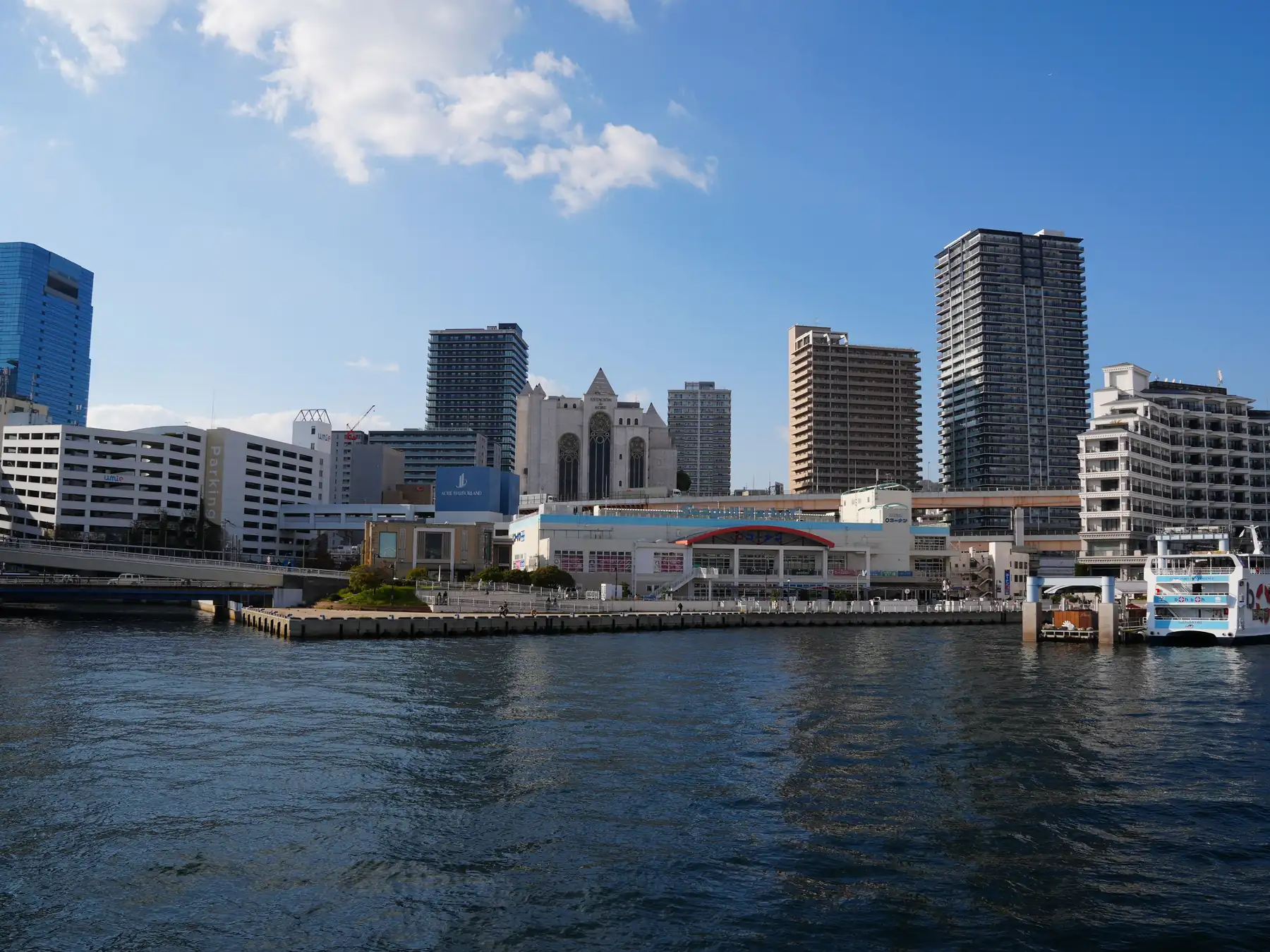 Modern buildings along the Kobe Port waterfront beneath clear blue skies.