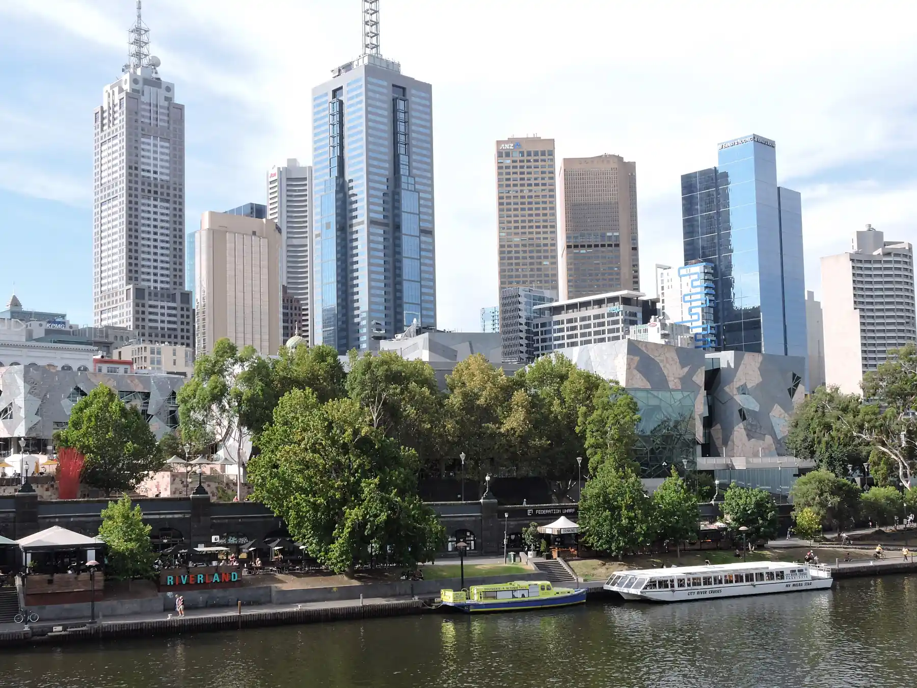 Melbourne city skyline rising above the Yarra River and waterfront greenery.