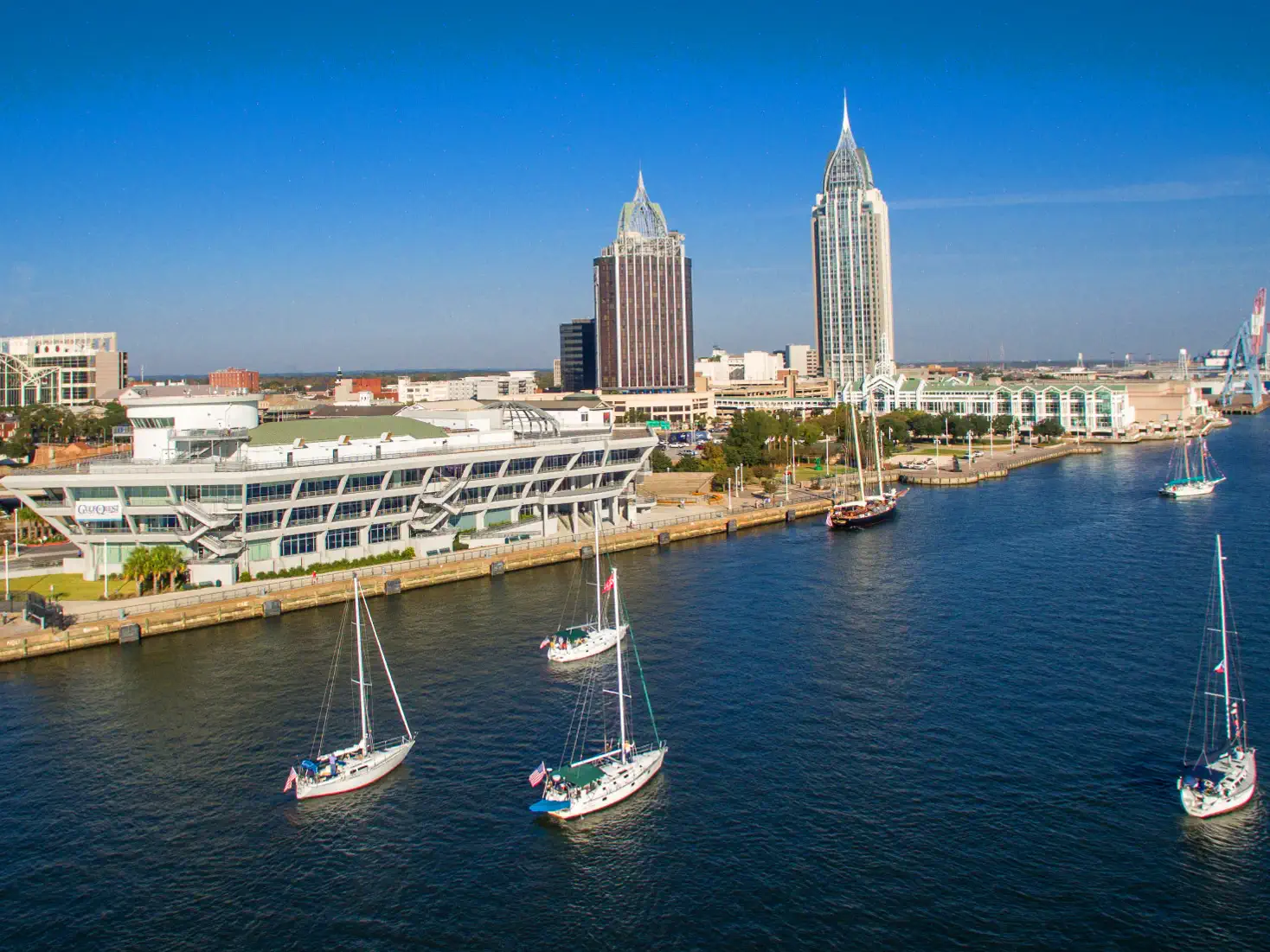 Sailboats on the Mobile, Alabama waterfront beneath the downtown skyline
