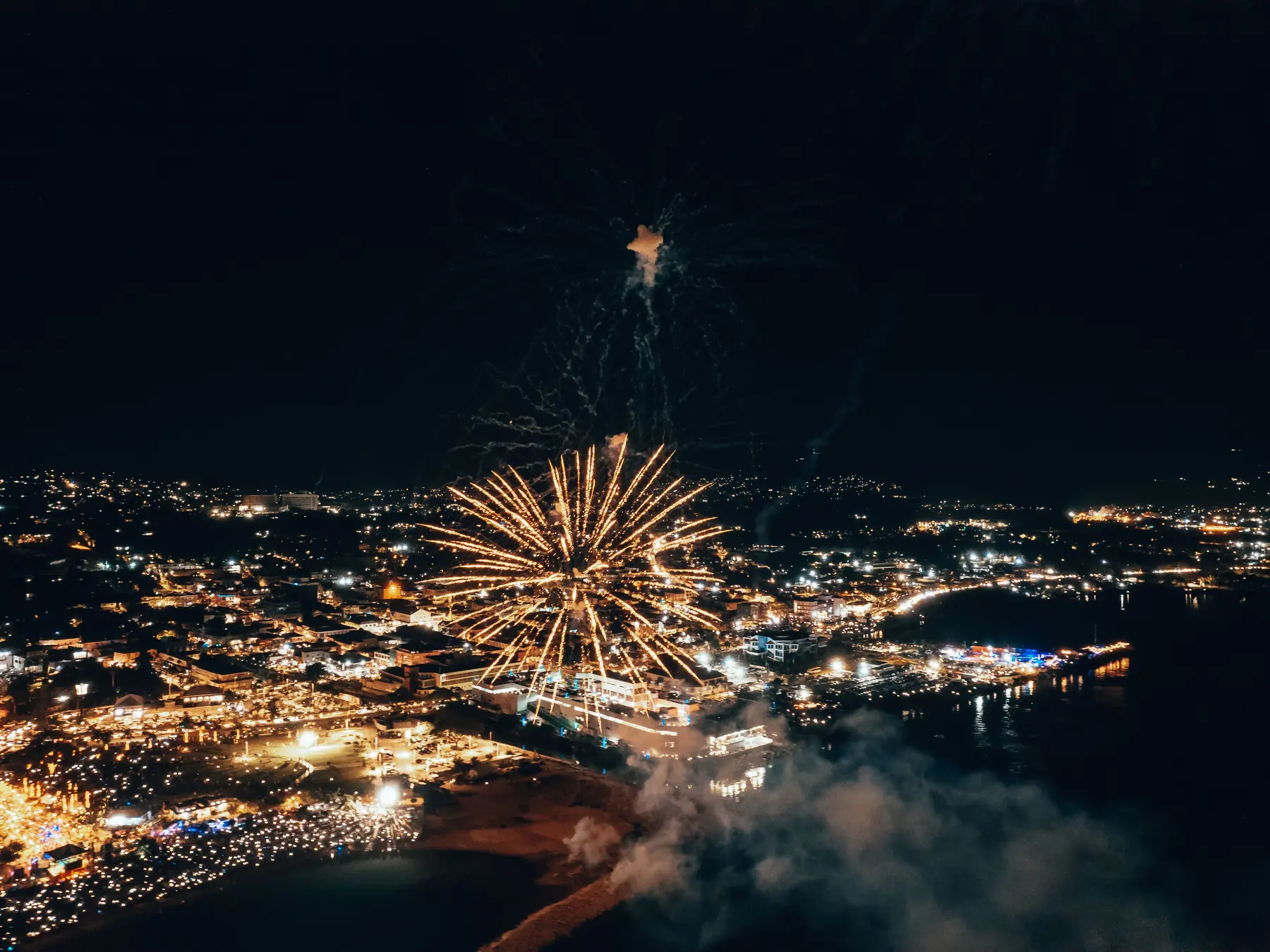Fireworks illuminate Montego Bay and its tropical city lights at night.