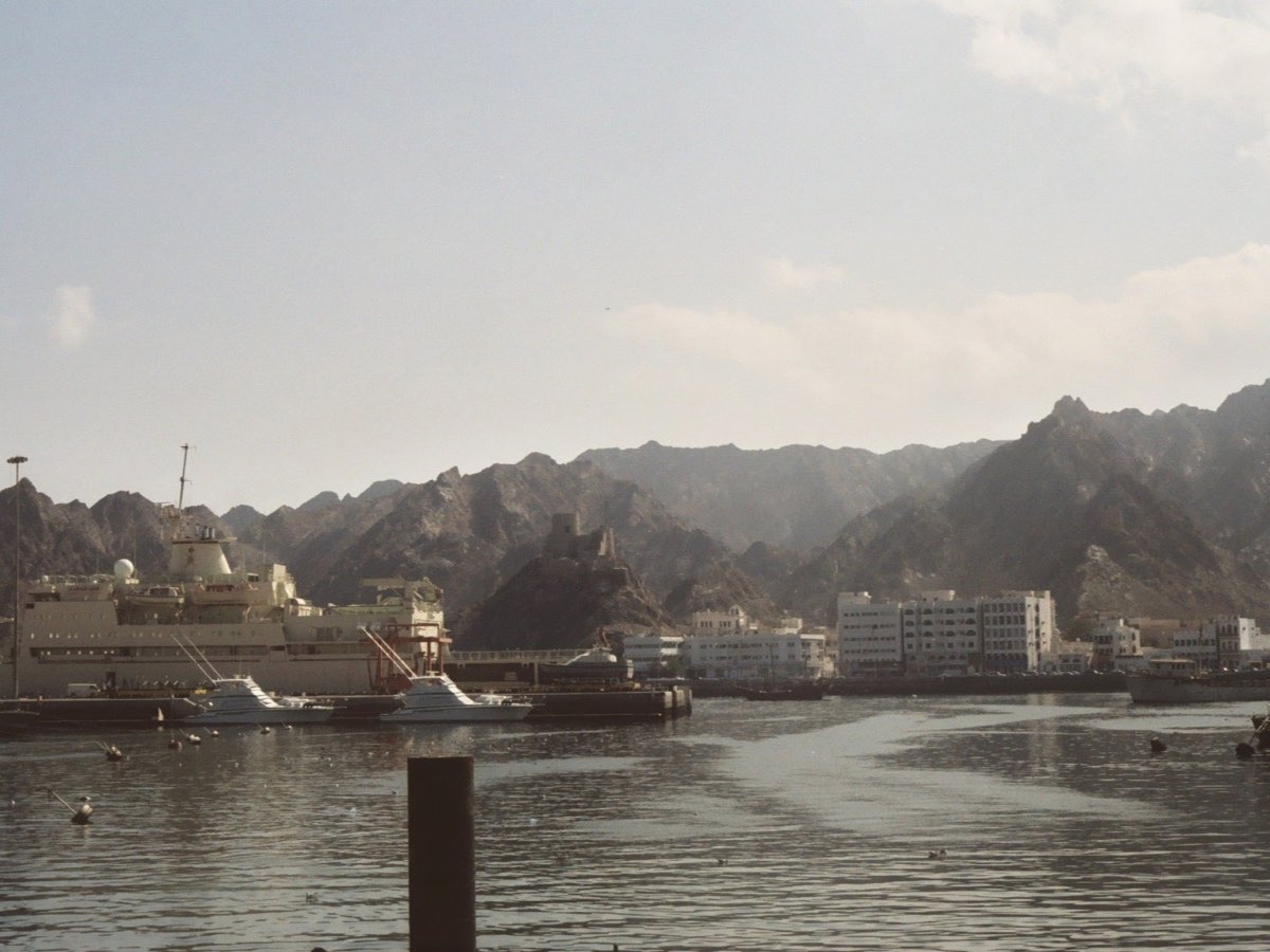 Muttrah harbor and waterfront below rugged mountains in Muscat
