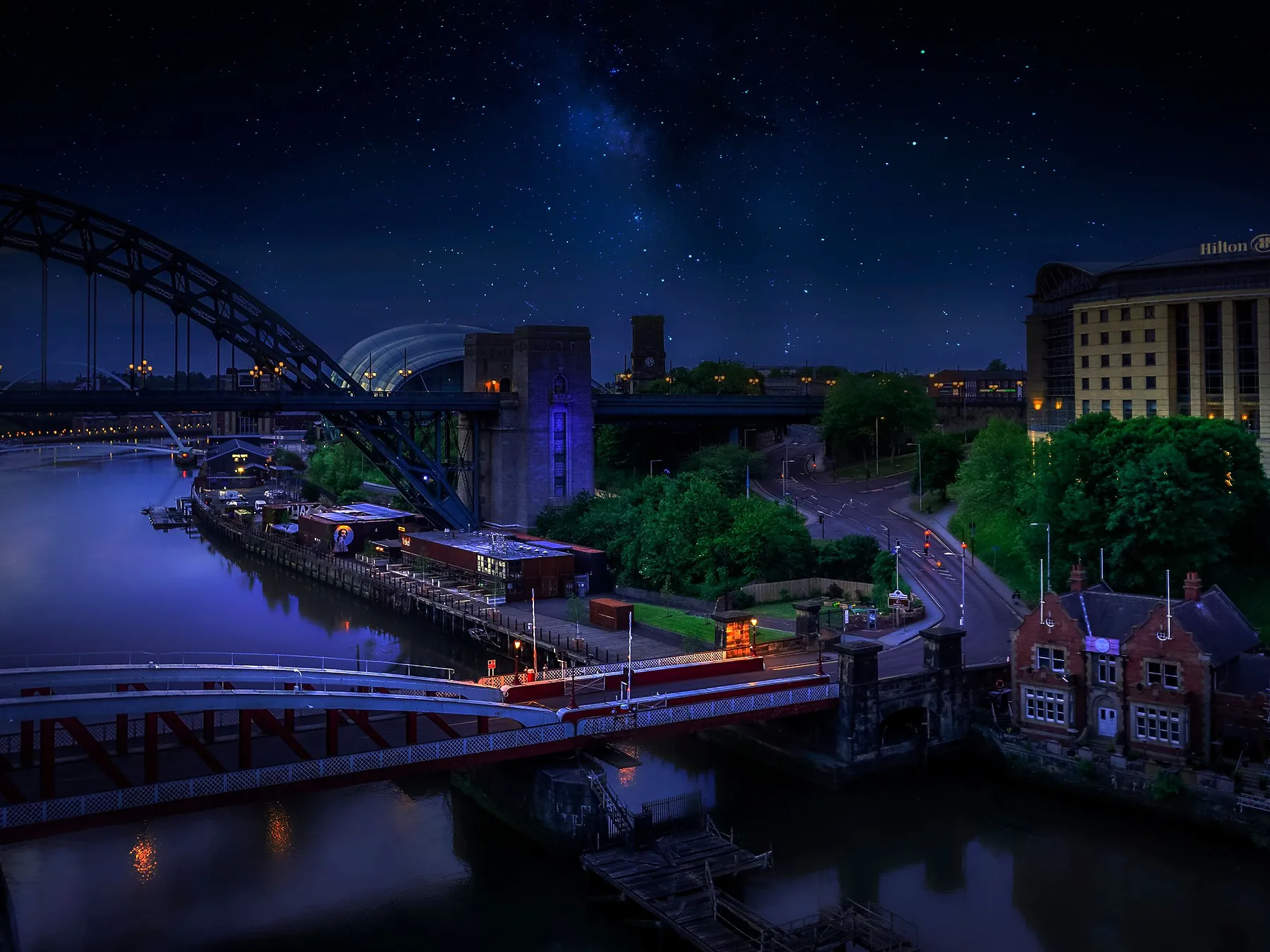 Tyne Bridge and Newcastle's waterfront illuminated above the River Tyne at night.