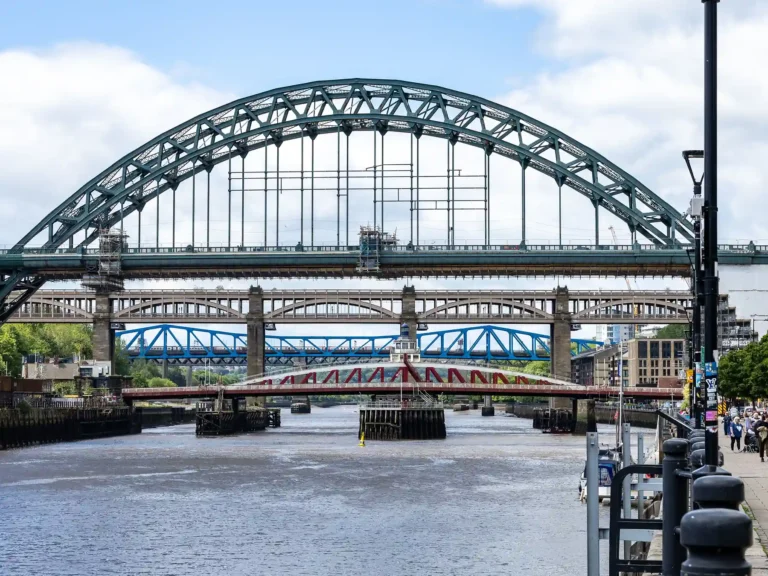 Tyne Bridge spanning the River Tyne beside Newcastle's waterfront on a sunny day.