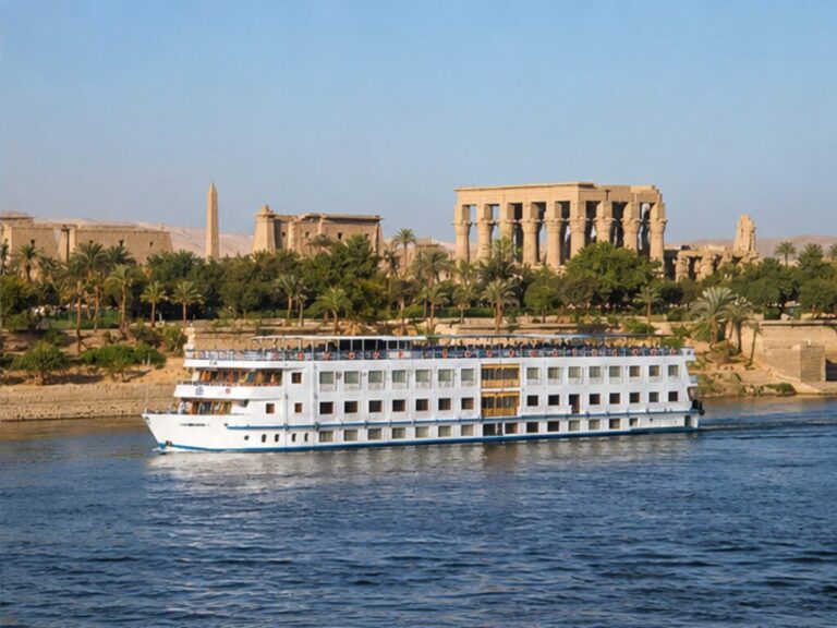 Classic Nile cruise ship sailing past Luxor's palm-lined riverbank and ancient temples