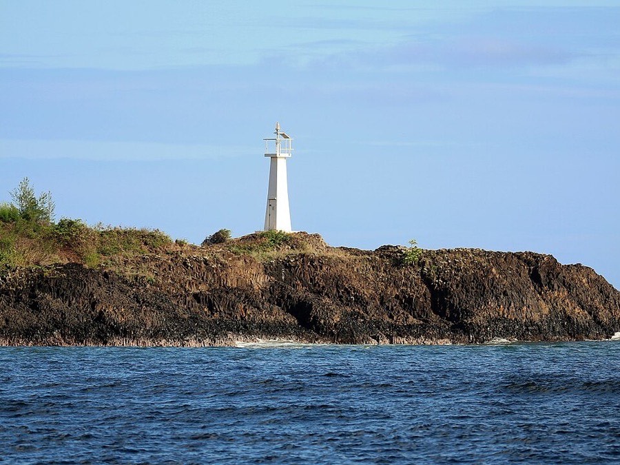 White navigation beacon on the rocky shoreline at Ninini Point in Nawiliwili Bay