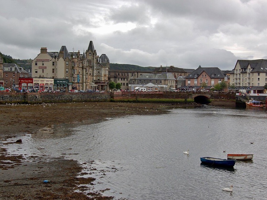 Stone buildings and small boats along the Oban waterfront at low tide