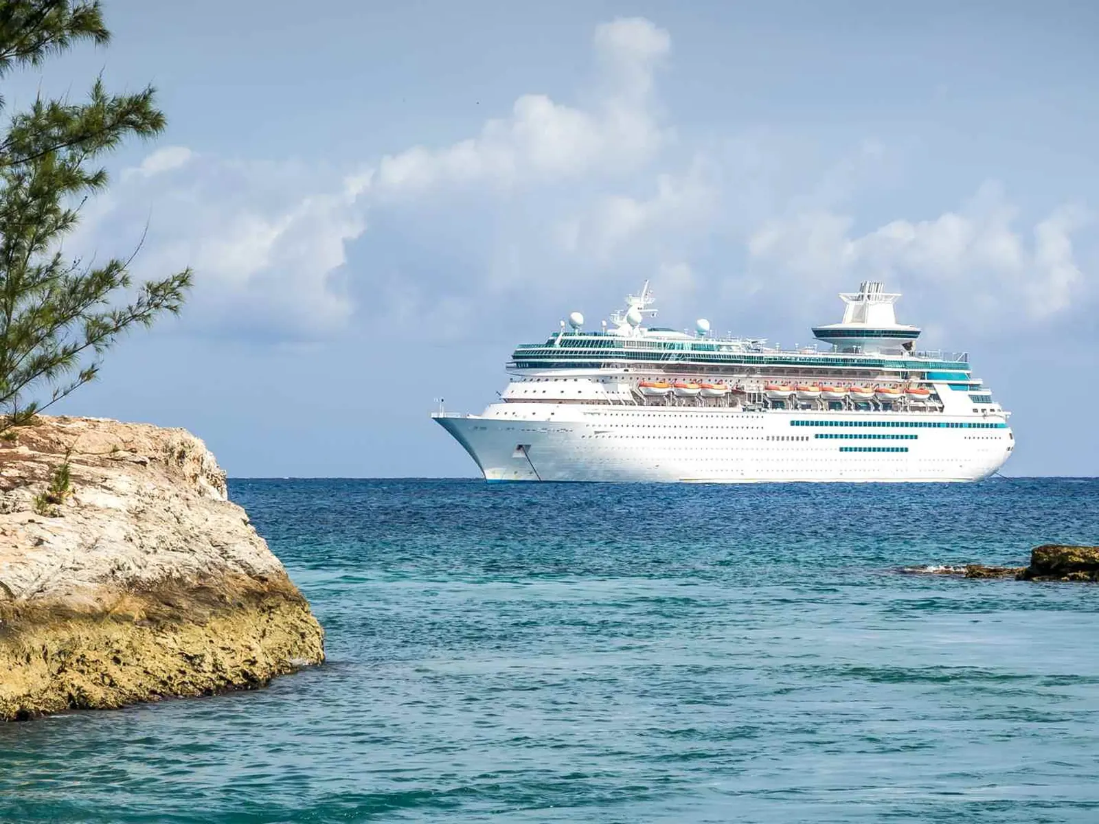 Cruise ship sailing offshore near a rocky Mediterranean coast
