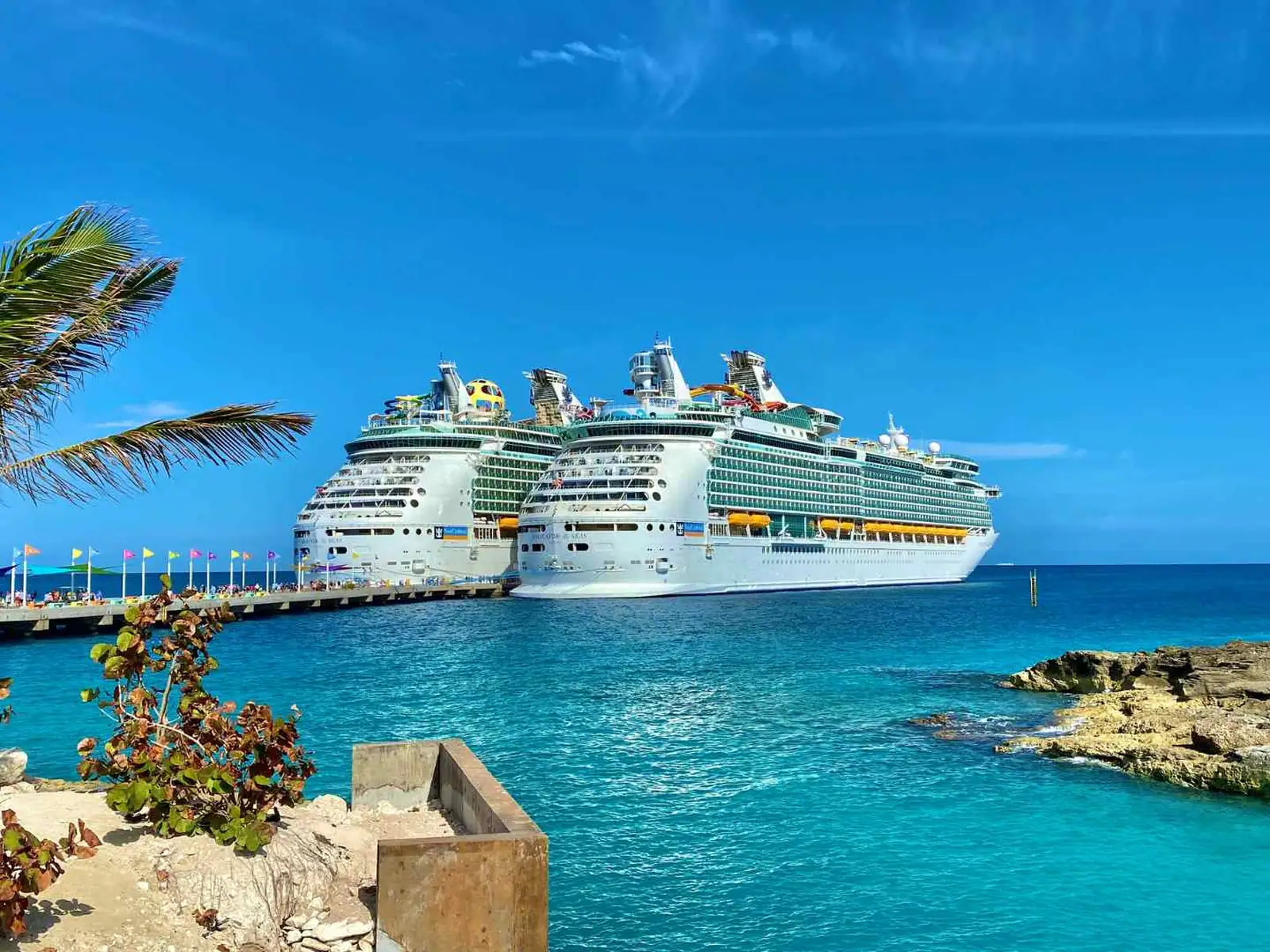Two cruise ships docked at a tropical island pier