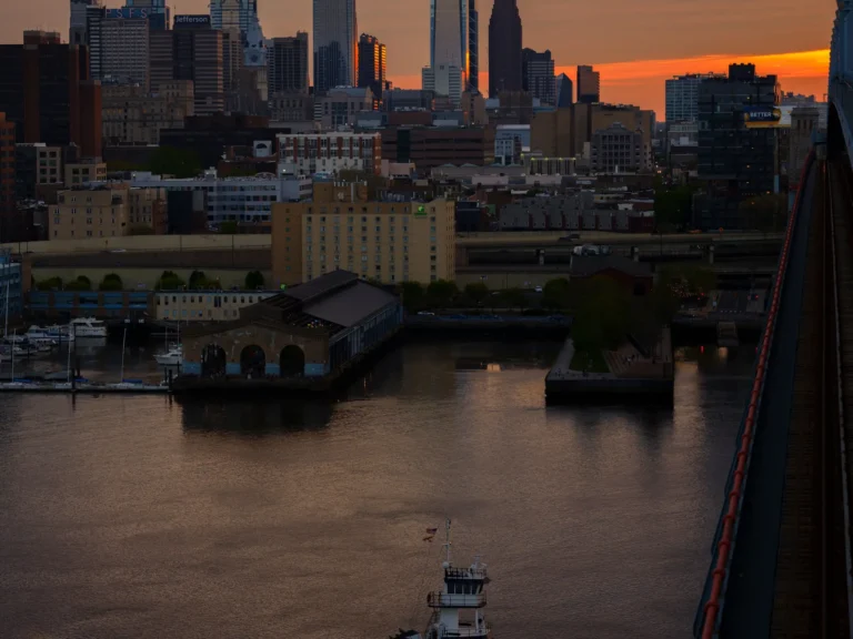 Philadelphia skyline and waterfront at sunset with a boat on the river