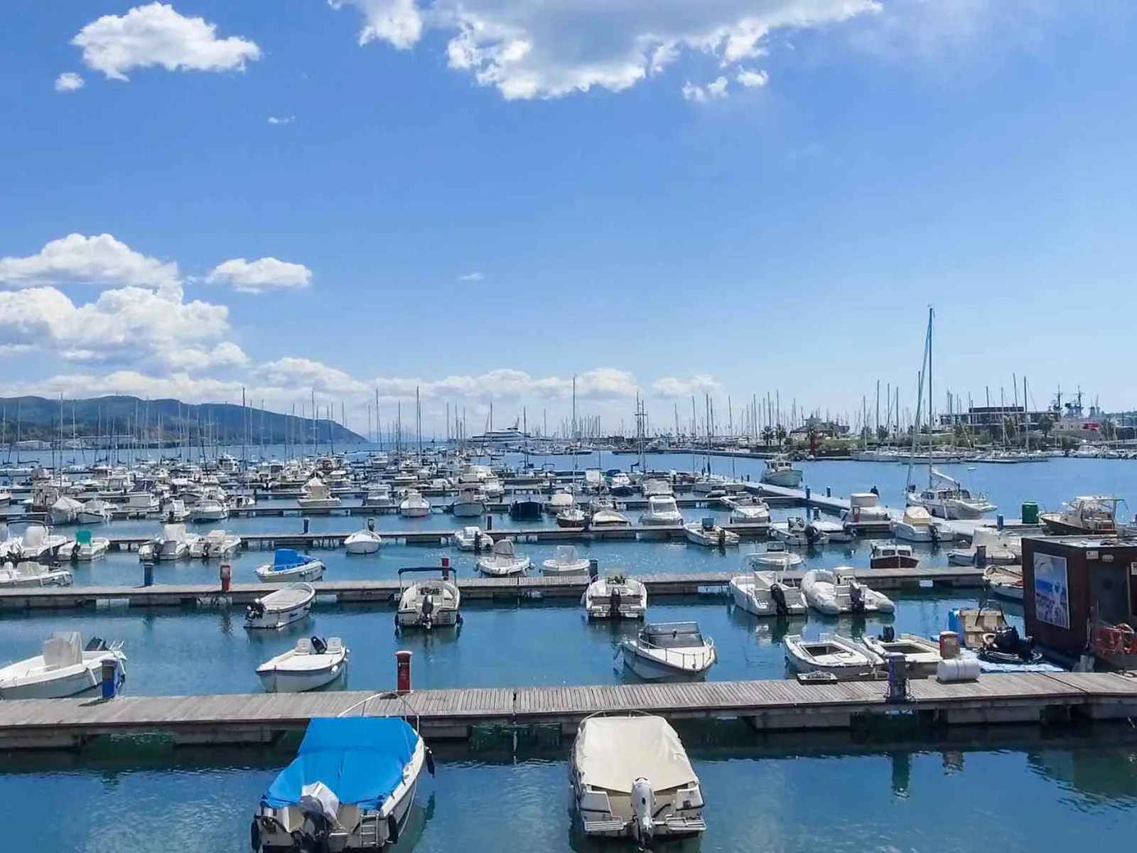 Yachts moored in La Spezia marina beneath coastal hills