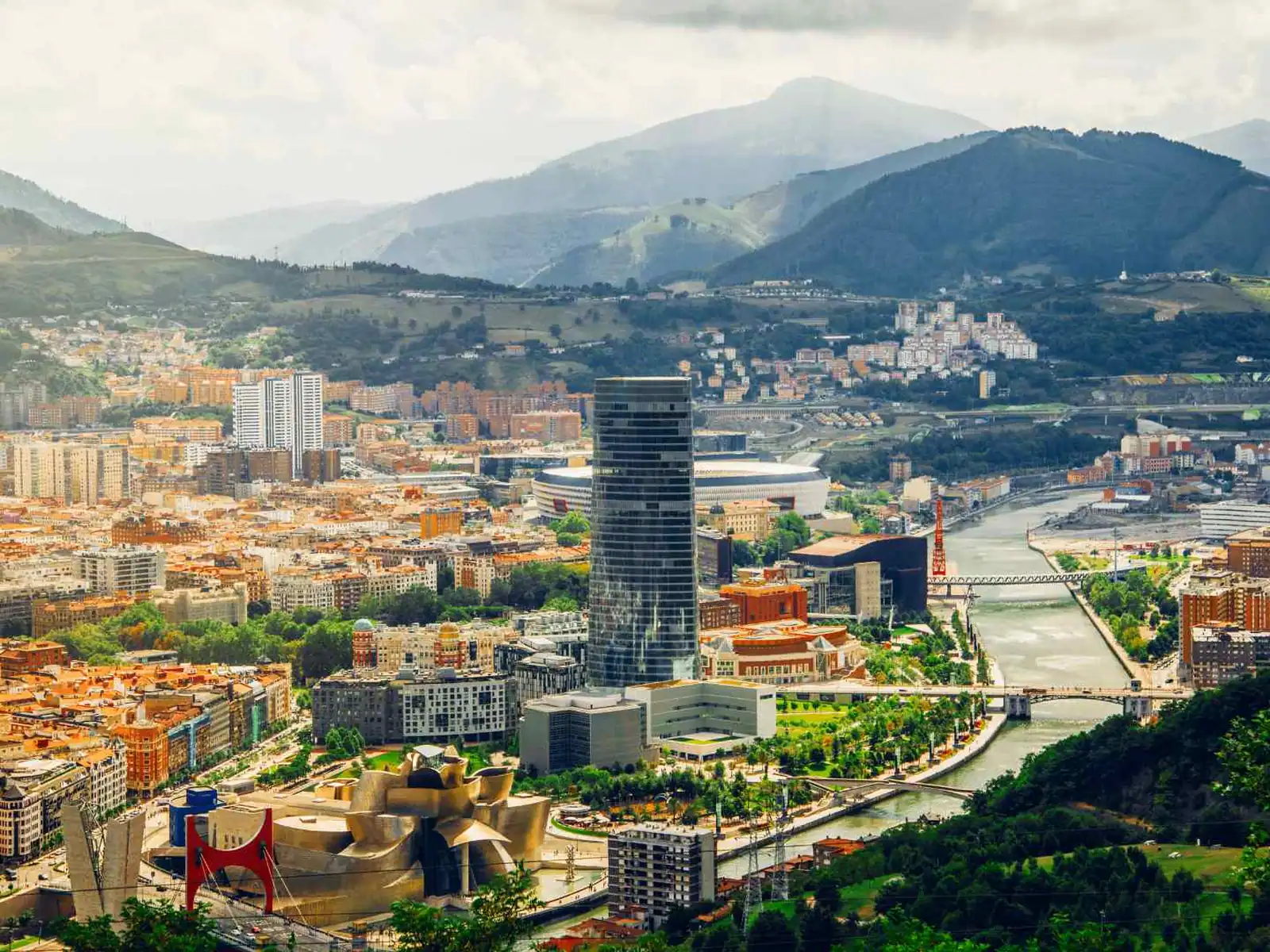 Aerial panorama of Bilbao surrounded by green Basque hills