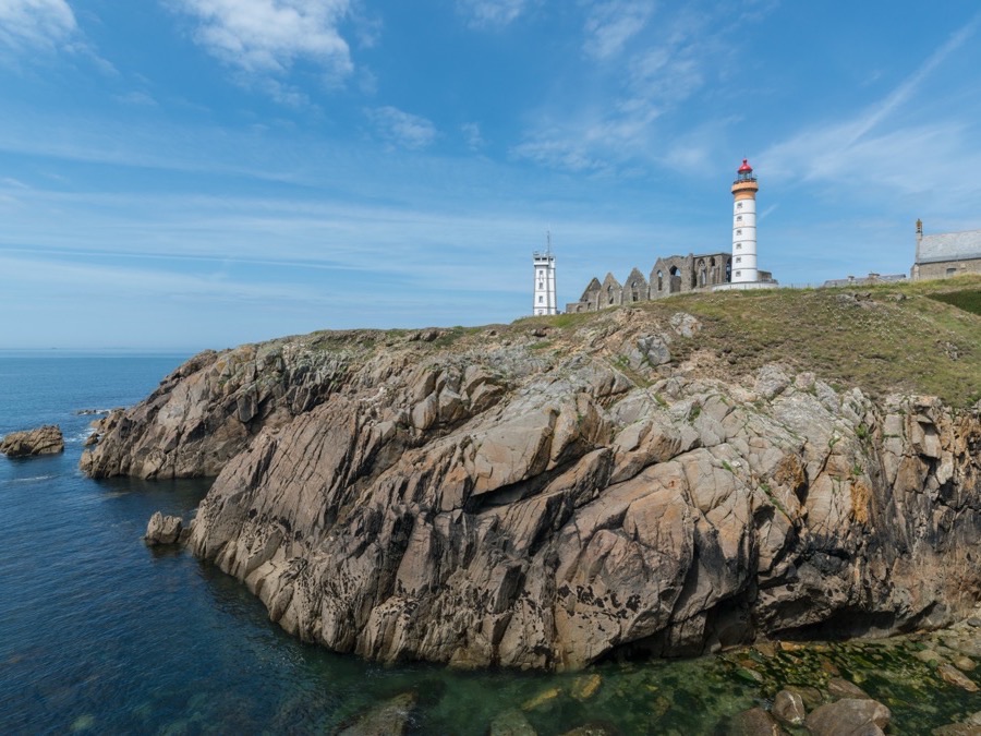 Pointe Saint-Mathieu lighthouse and abbey ruins above rocky cliffs in Brittany