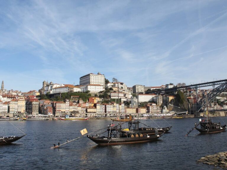 Rabelo boats cruising on the Douro River beside Porto's Ribeira waterfront