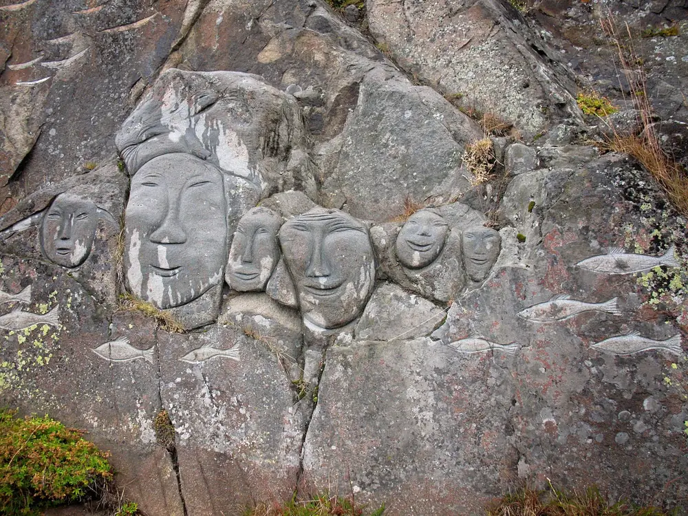 Carved stone faces and fish in the Stone and Man open-air artwork in Qaqortoq