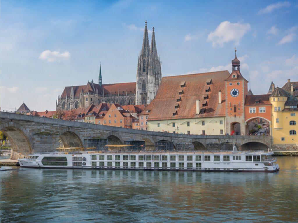 River cruise ship beside Regensburg's UNESCO old town and historic Stone Bridge