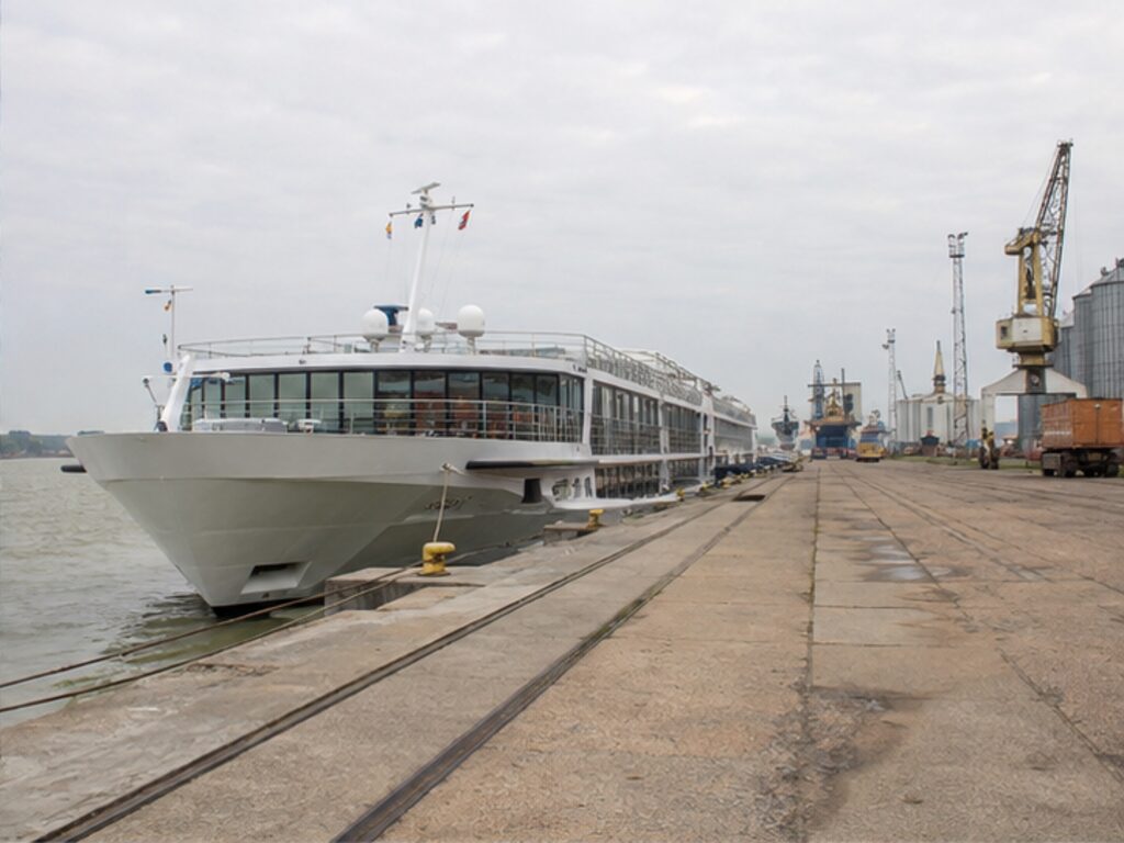 River cruise ship tied at an industrial quay far from a European city center