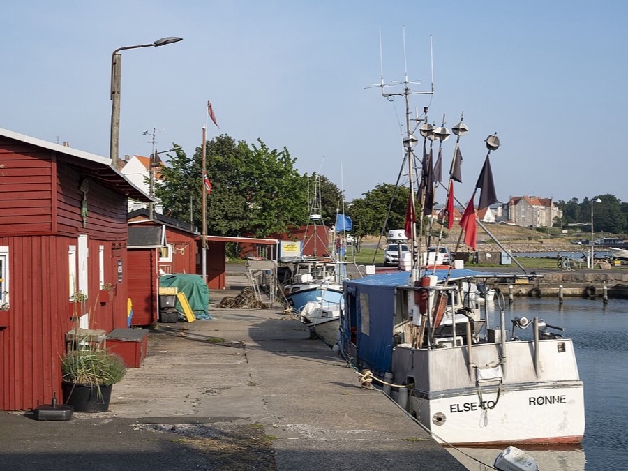 Fishing boats moored beside red harbor buildings in Rønne, Bornholm