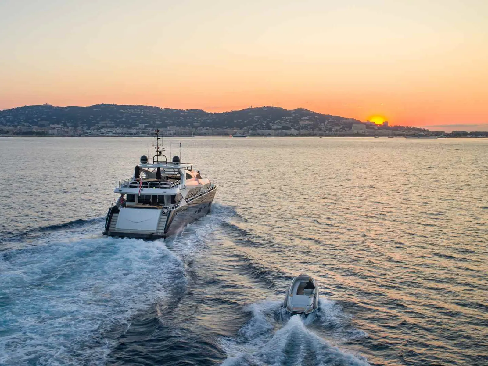 Cruise tender crossing calm water toward shore at sunset