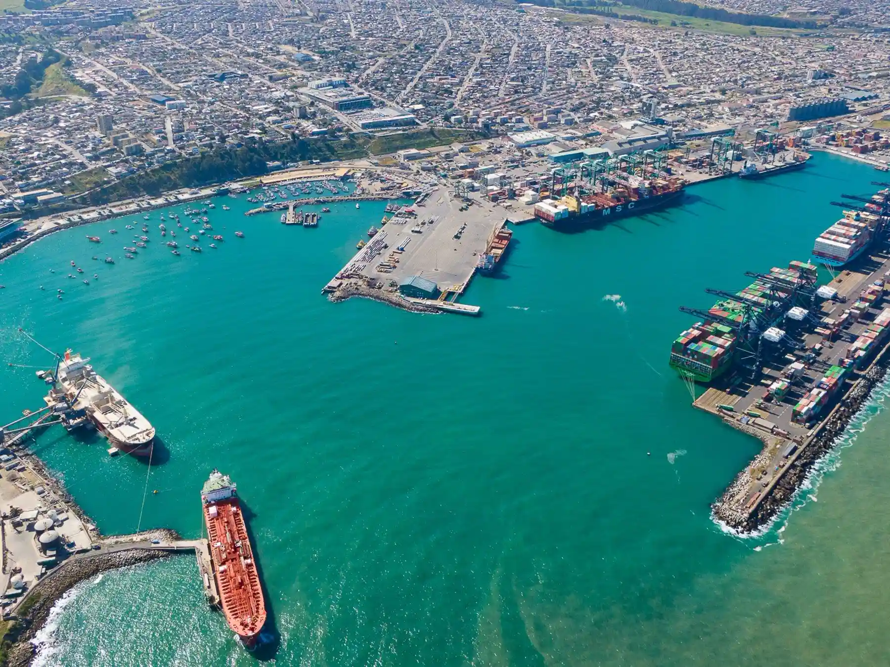 Aerial view of ships, fishing boats, and cargo terminals in San Antonio harbor.