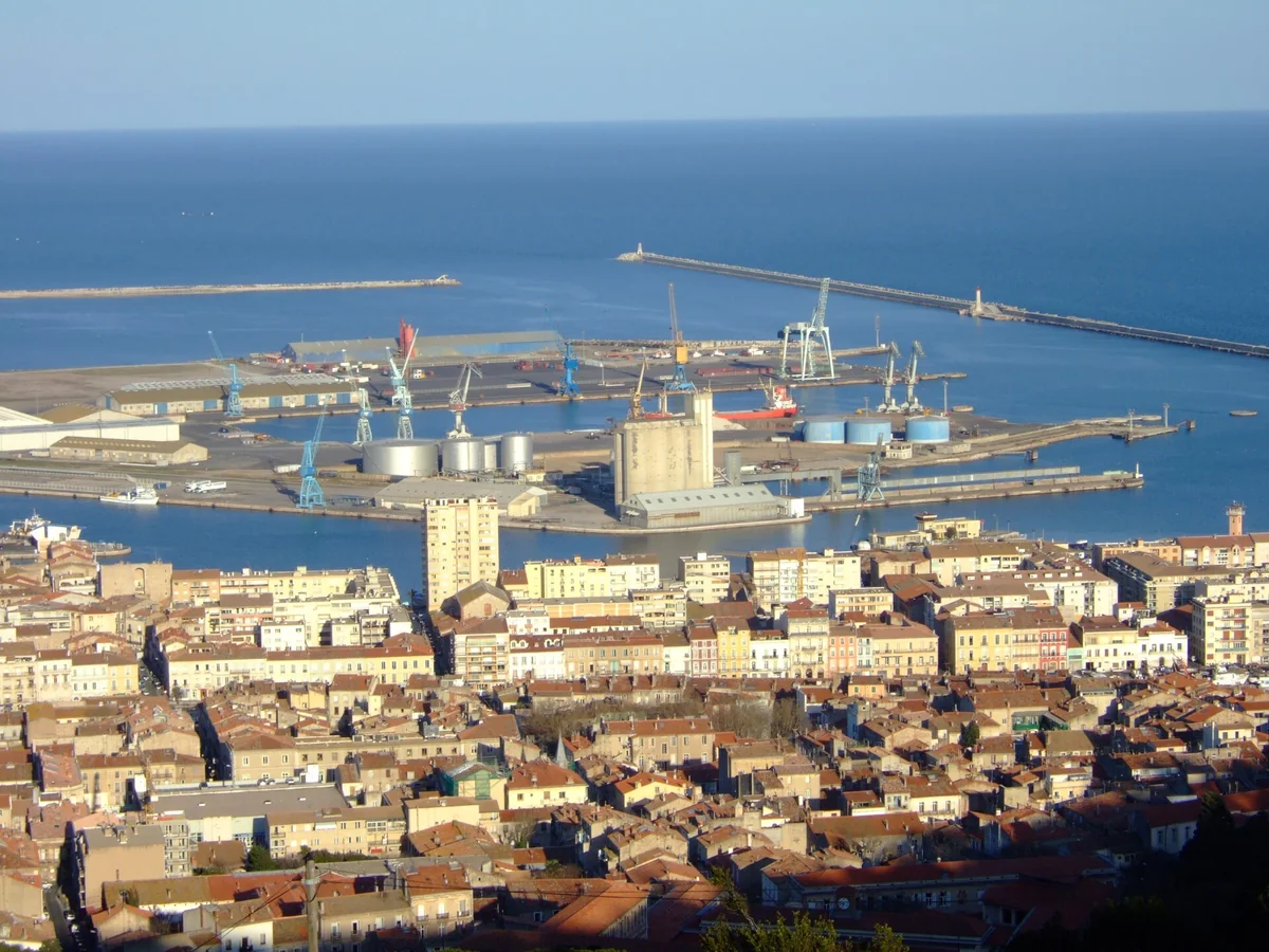 Commercial harbour, breakwaters, and city rooftops in Sète