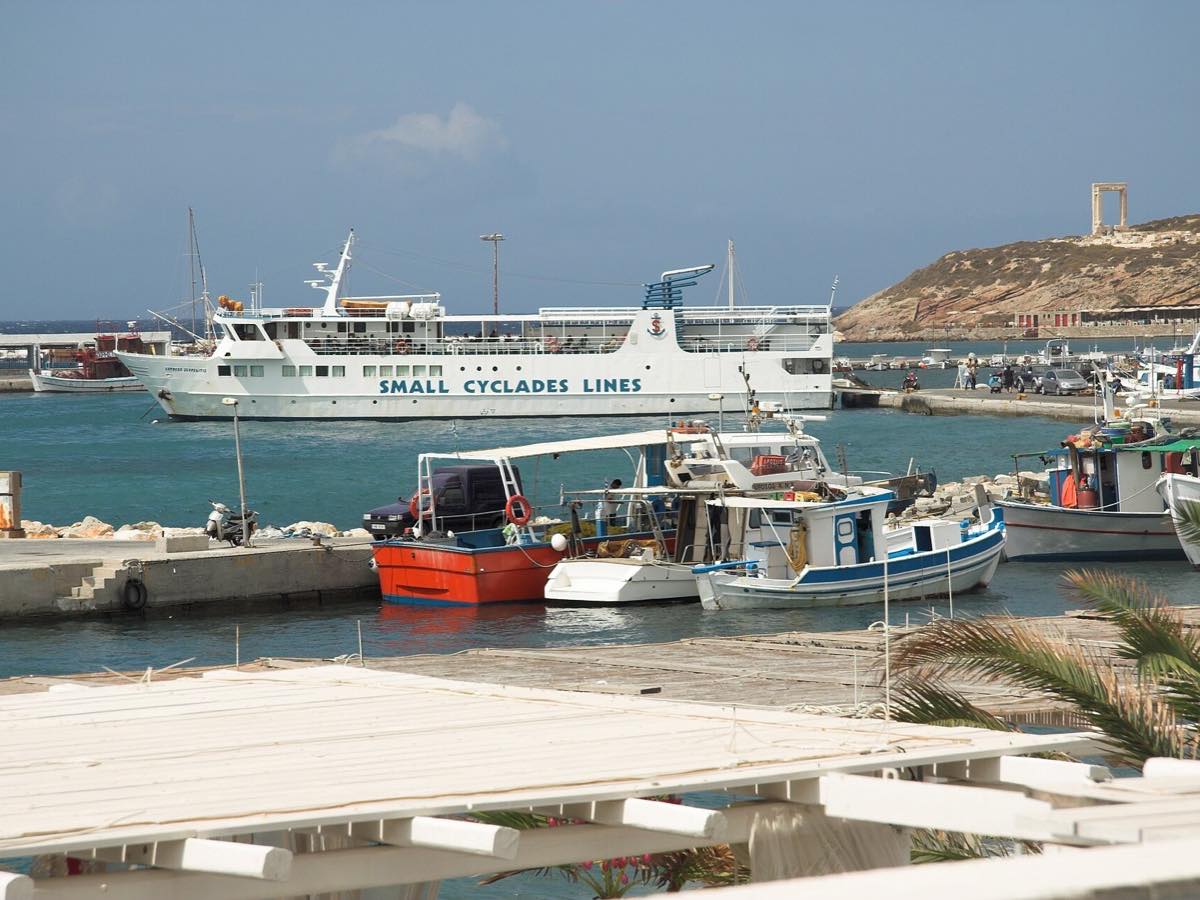 Small Cyclades ferry and fishing boats in Naxos harbor with the Portara beyond
