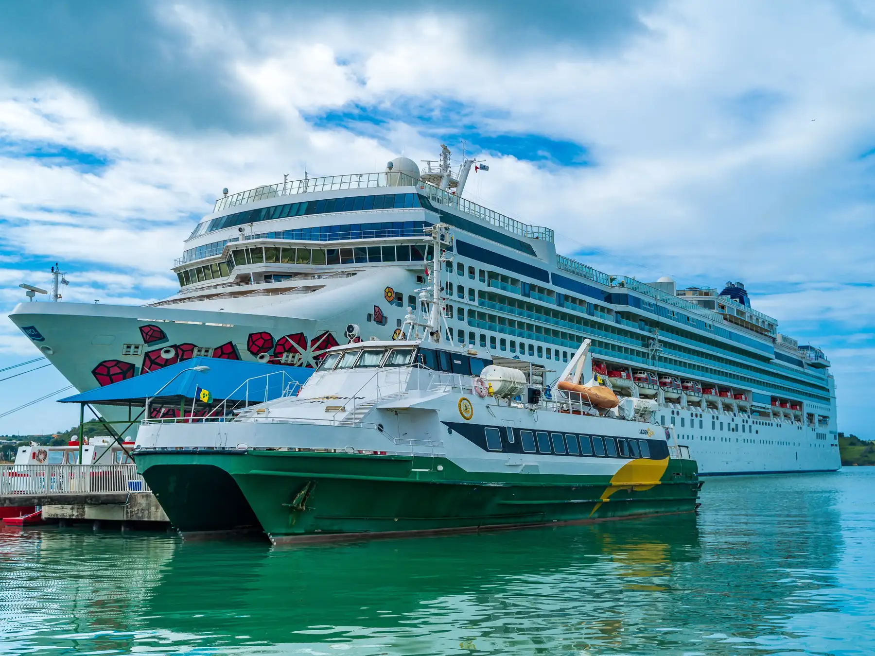 Cruise ship and ferry docked beside the pier in Antigua's turquoise water.