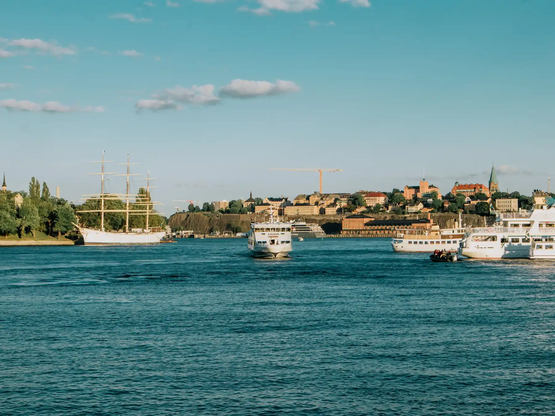 Passenger boats crossing Stockholm harbor with the city waterfront behind them.