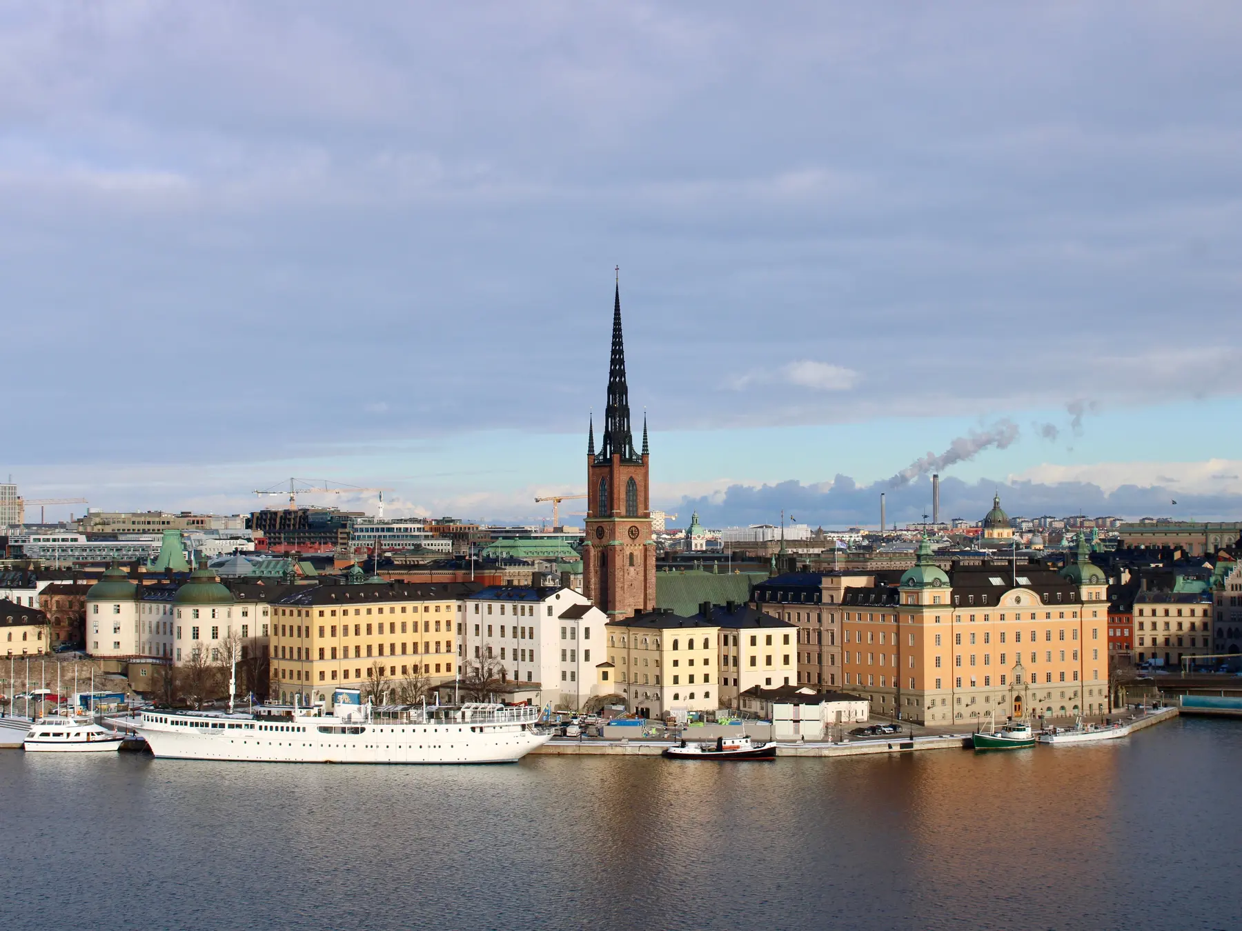 Historic Riddarholmen buildings and church spire beside Stockholm's waterfront.