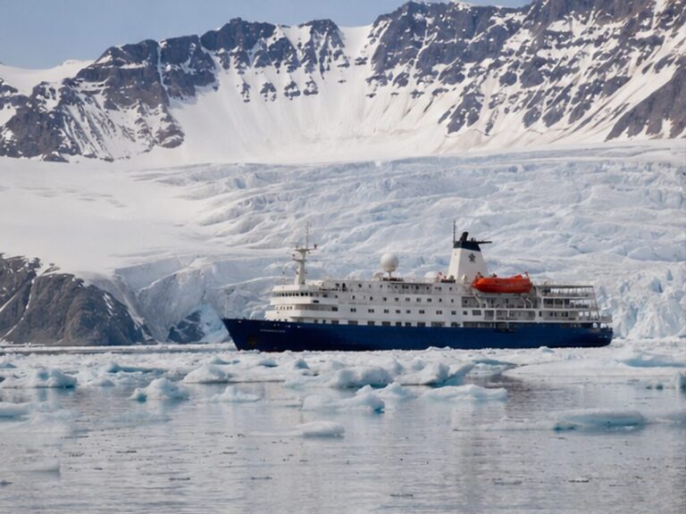 Small expedition cruise ship near a glacier and sea ice in Svalbard