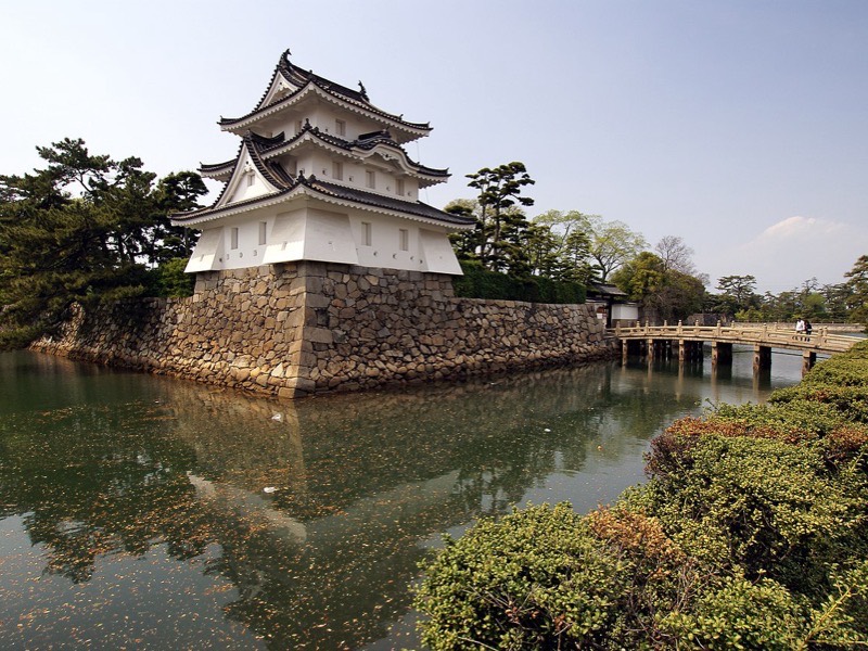 White turret of Takamatsu Castle reflected in its surrounding moat