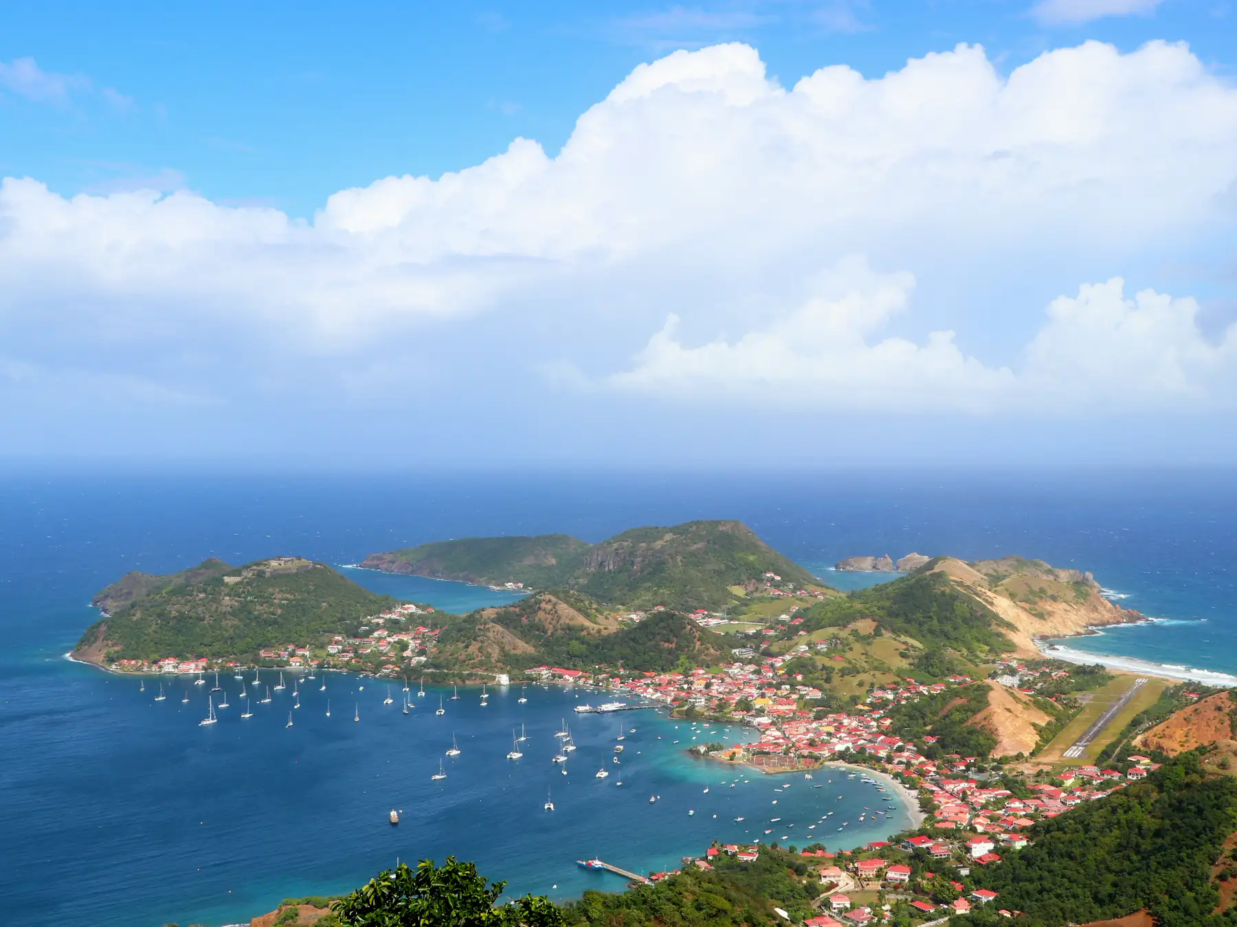 Harbor filled with boats beside green hills in Terre-de-Haut, Guadeloupe