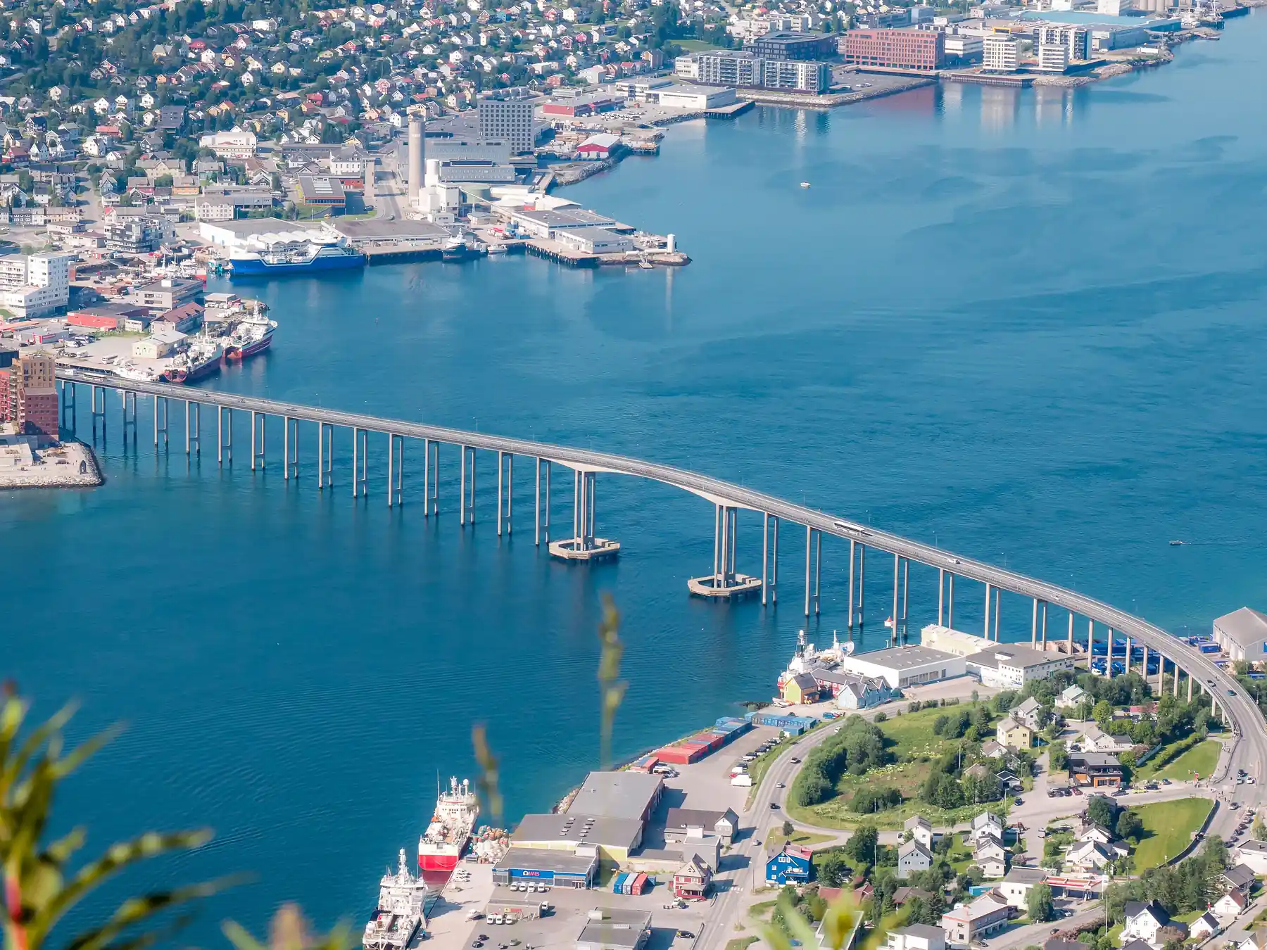 Aerial view of Tromsø, its bridge, harbor, and surrounding fjord landscape.
