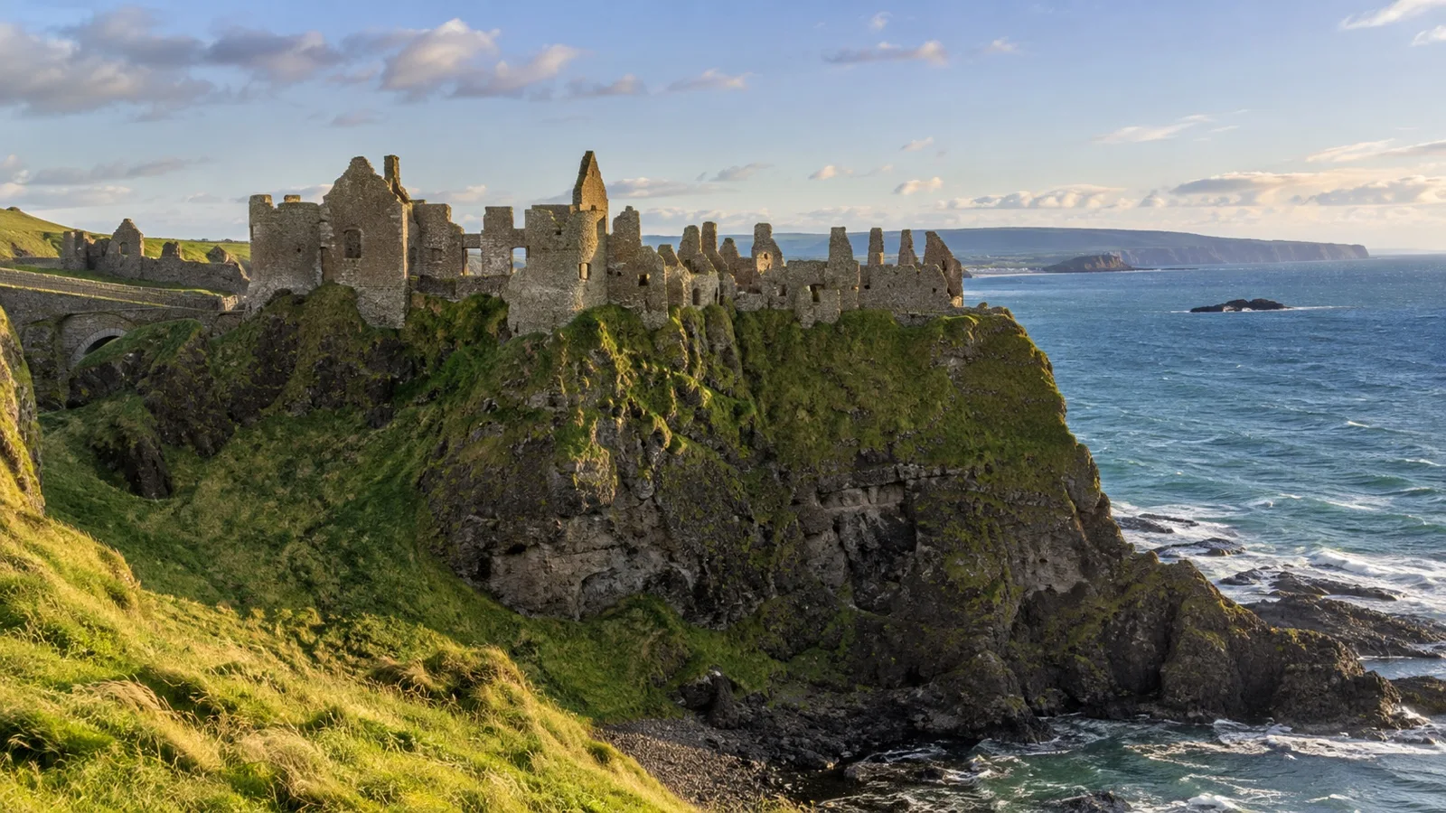 Dunluce Castle ruins on a cliff above the sea.