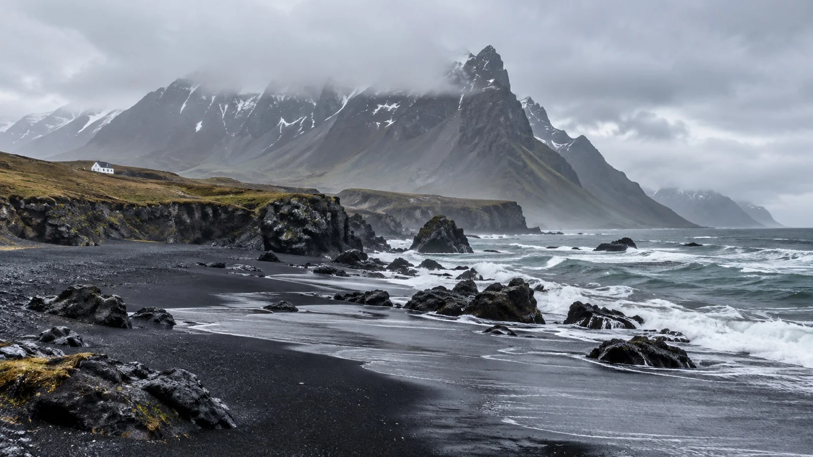 Iceland black volcanic shoreline beneath misty mountains.
