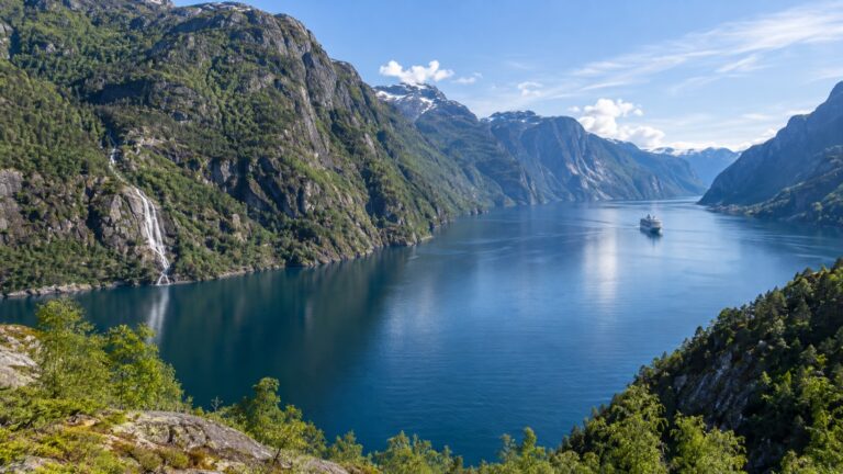 Cruise ship amid steep green mountains and blue water of Åkrafjorden