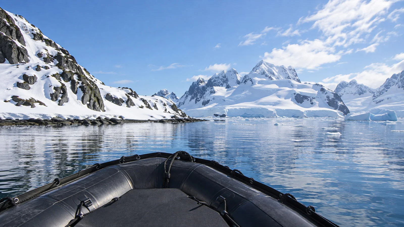 Empty inflatable Zodiac boat on calm water approaching a snowy Antarctic Peninsula landing