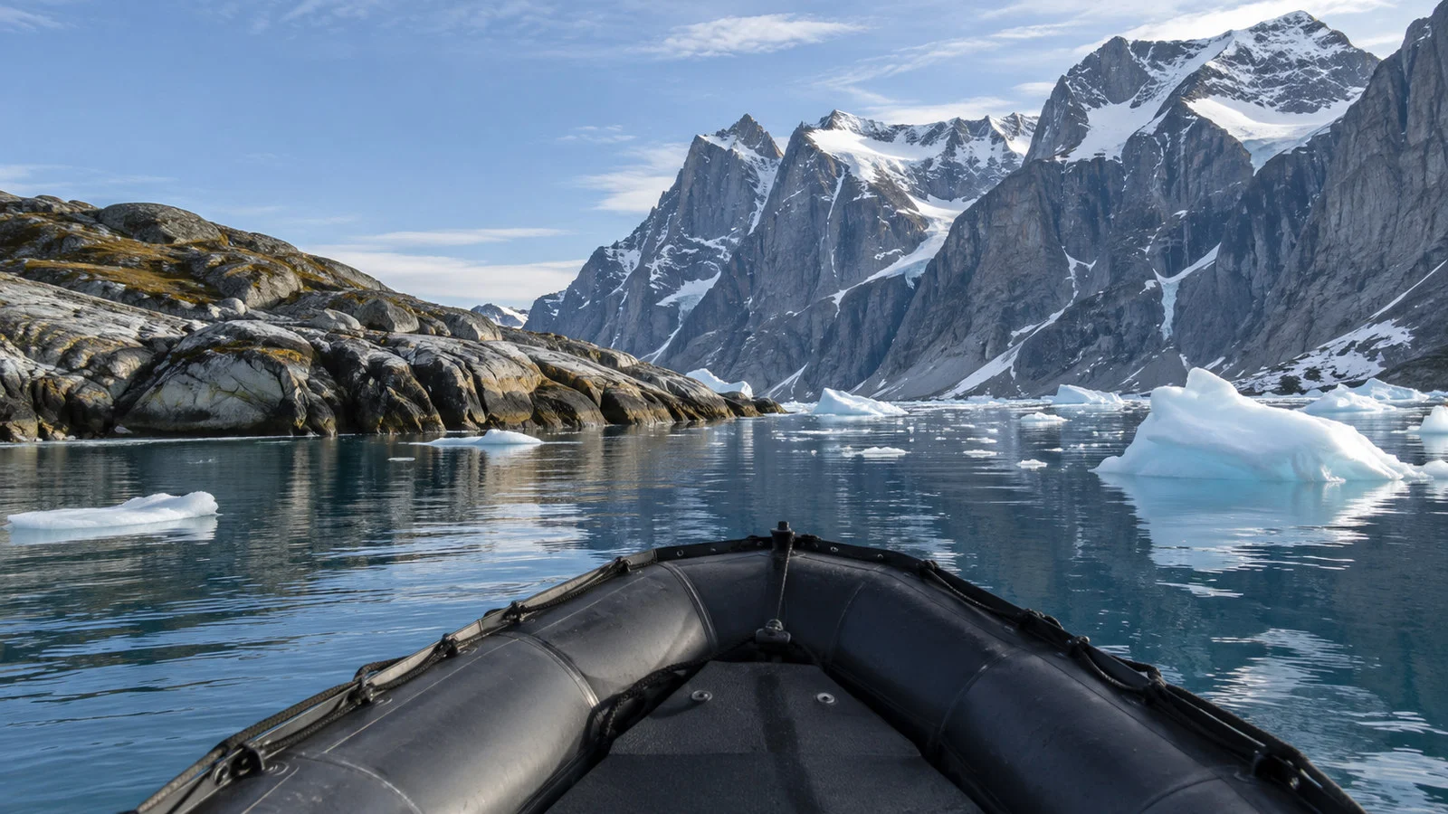Empty expedition Zodiac inflatable boat approaching rocky Baffin Island Arctic landing with small icebergs, no people