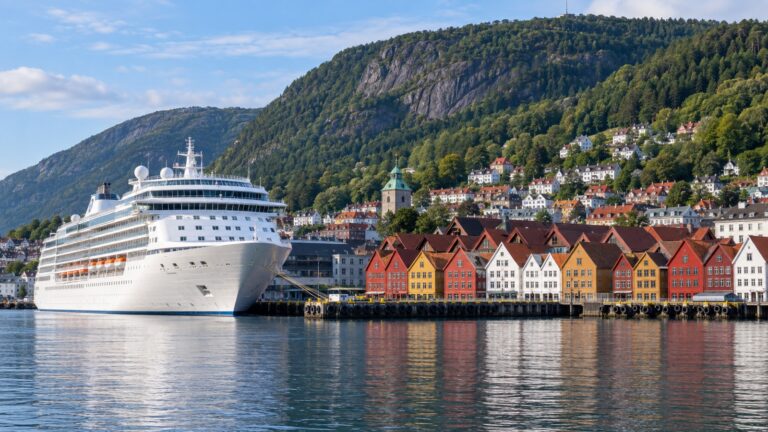 Bergen cruise pier at Skolten with a white cruise ship docked beneath colorful Bryggen buildings and steep green mountains