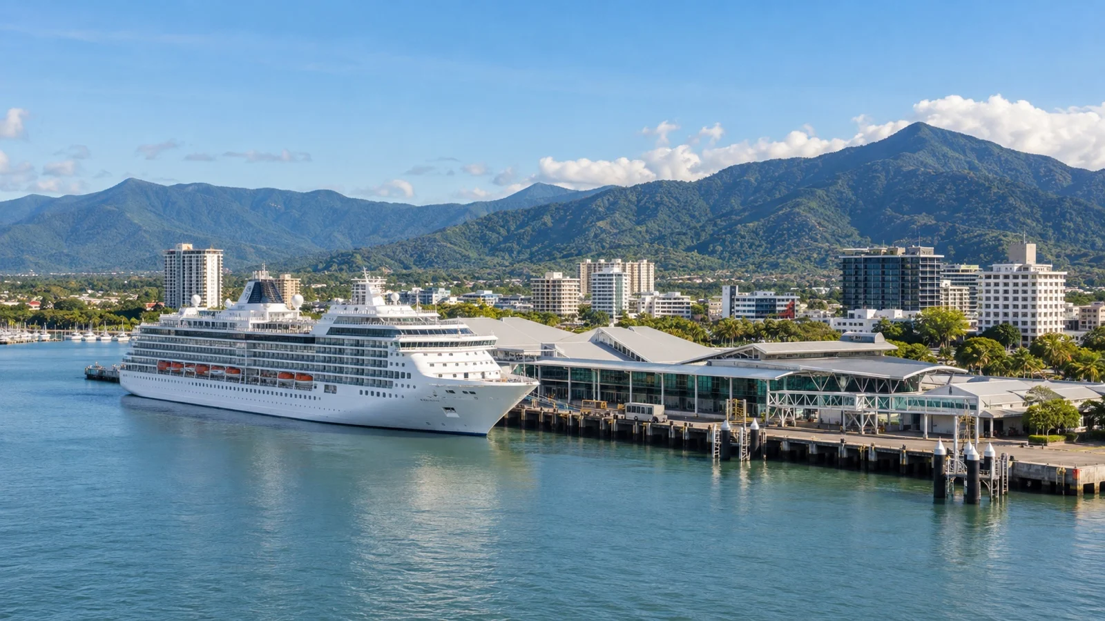 Cairns Cruise Liner Terminal with a white cruise ship docked on Trinity Inlet, tropical mountains and city behind