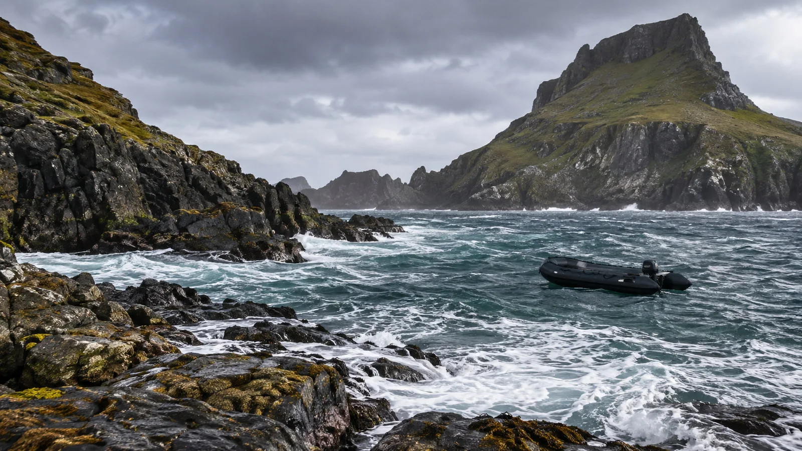 Cape Horn island landing cove with surf, rocky shore and empty expedition Zodiac held offshore by rough weather, no people