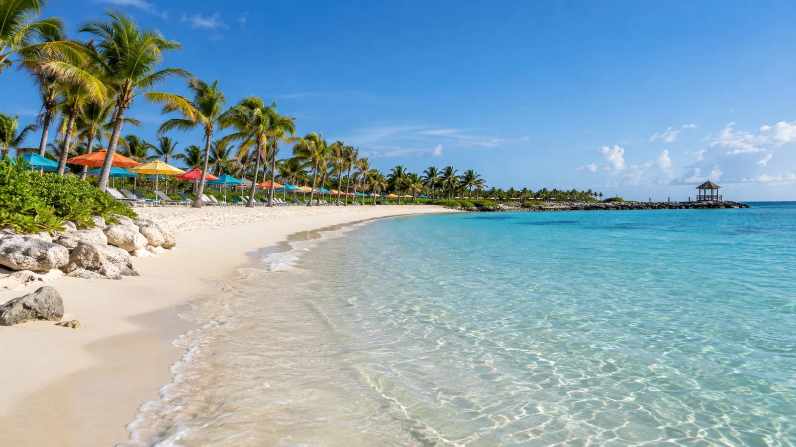 Empty Castaway Cay beach in the Bahamas with palms, colorful umbrellas, and clear shallow water