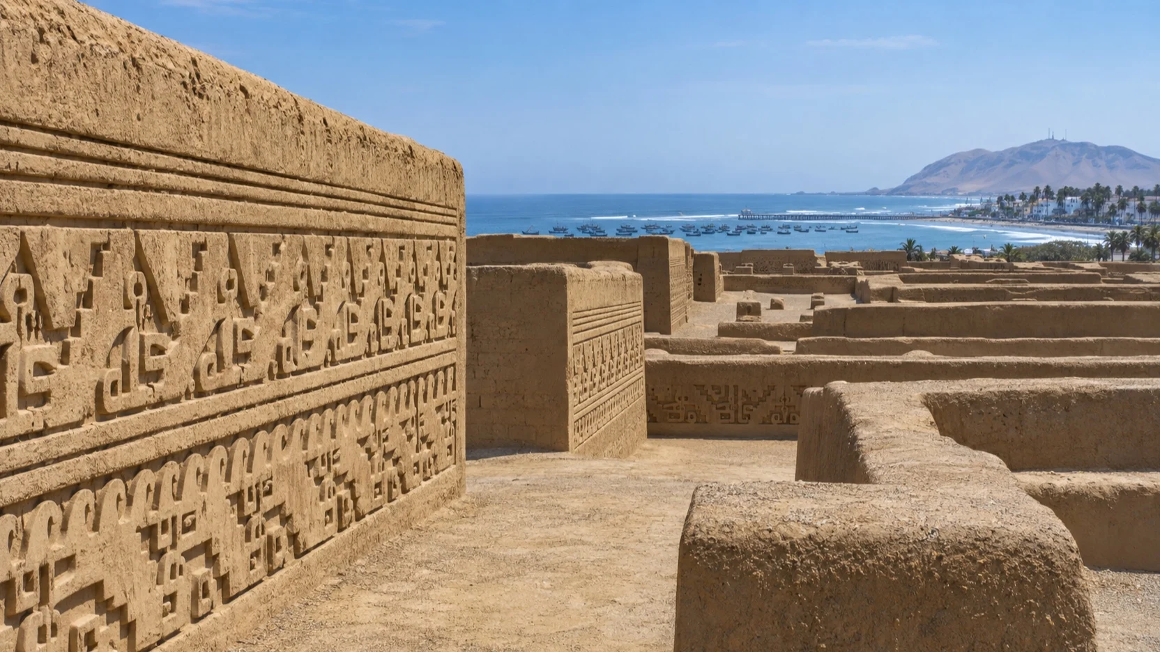 Intricate Chan Chan adobe walls with Peru's Pacific coast beyond