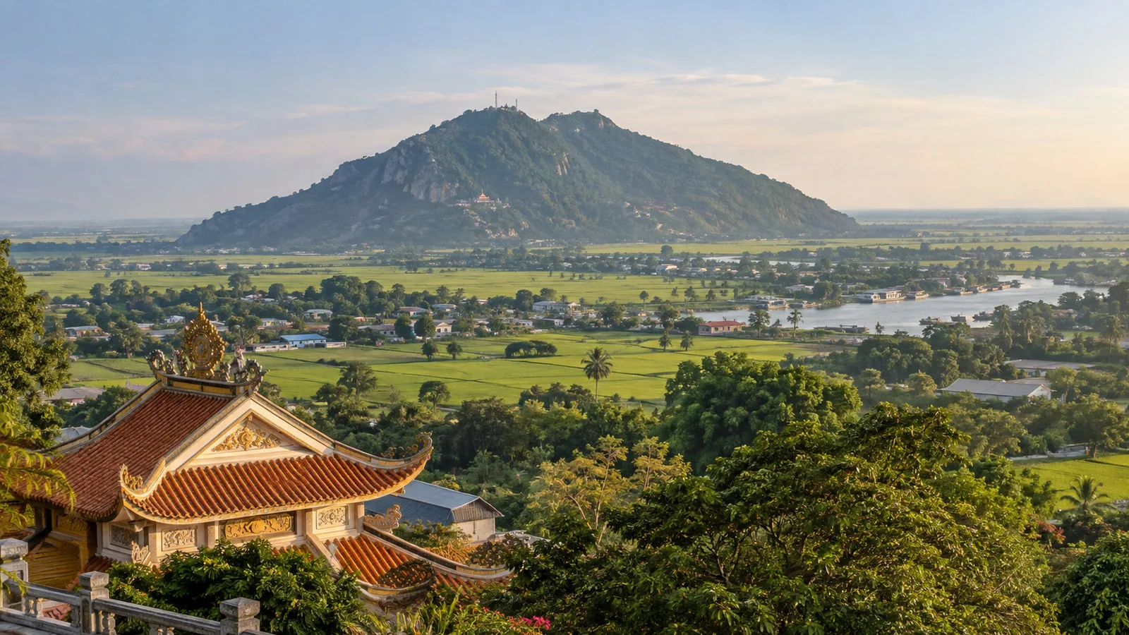 Sam Mountain rising above rice fields and lowland landscape near Chau Doc Vietnam with temple roof in foreground