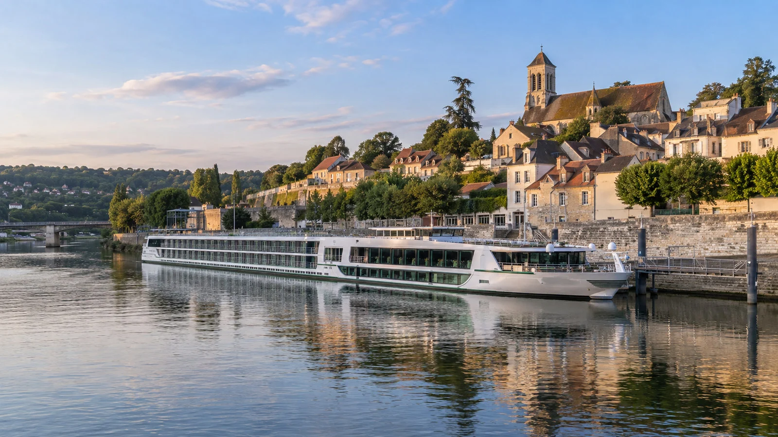 Seine river cruise vessel moored at Conflans-Sainte-Honorine France quay with old town above, no people