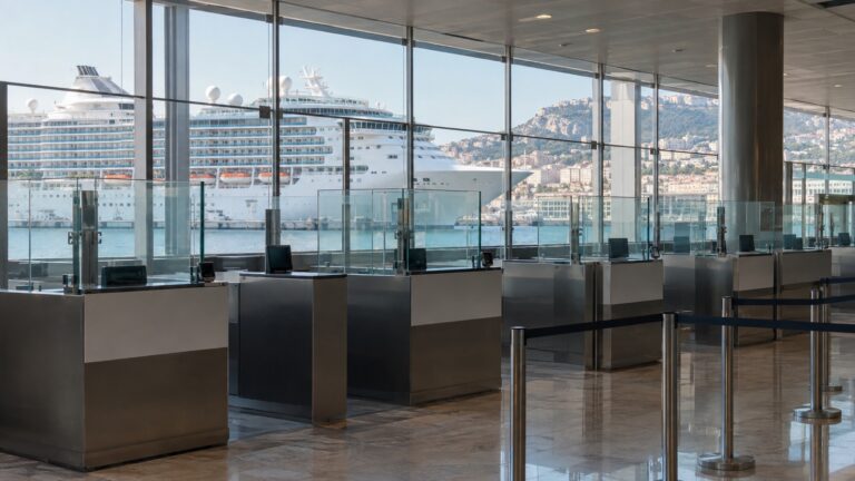 Empty passport inspection counters at cruise terminal with ship outside
