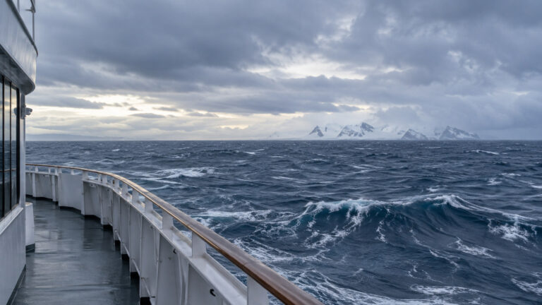 Expansive open Drake Passage sea from empty expedition ship deck under low grey Southern Ocean sky