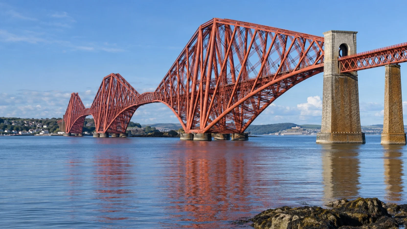 The red cantilever Forth Bridge crosses the Firth of Forth in Scotland
