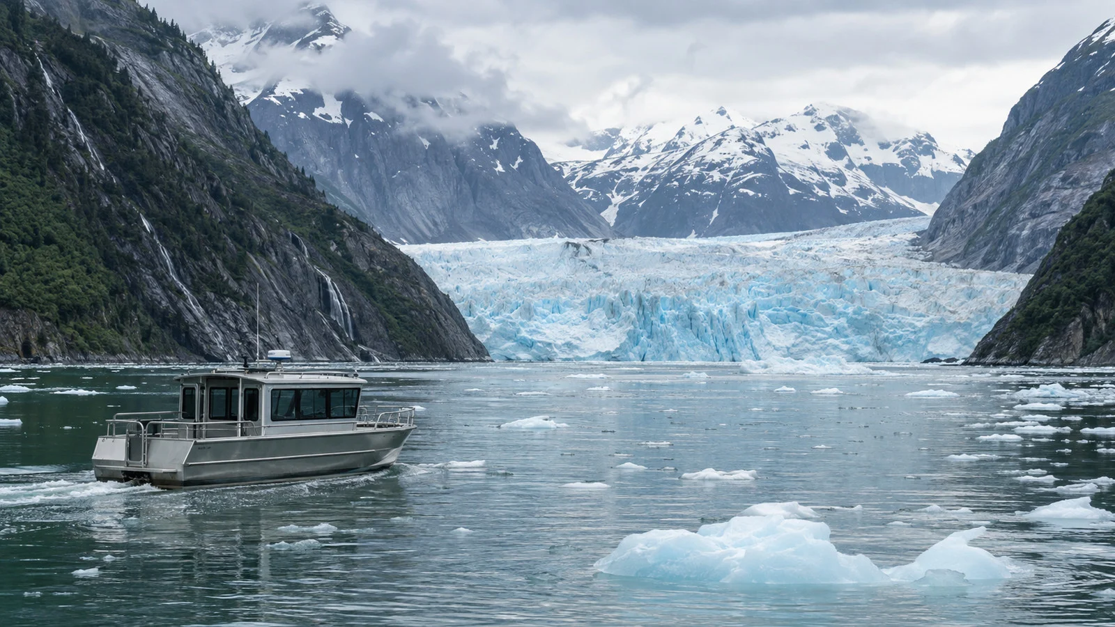 a small empty excursion boat cruising near Dawes Glacier amid floating ice with the glacier in the distance