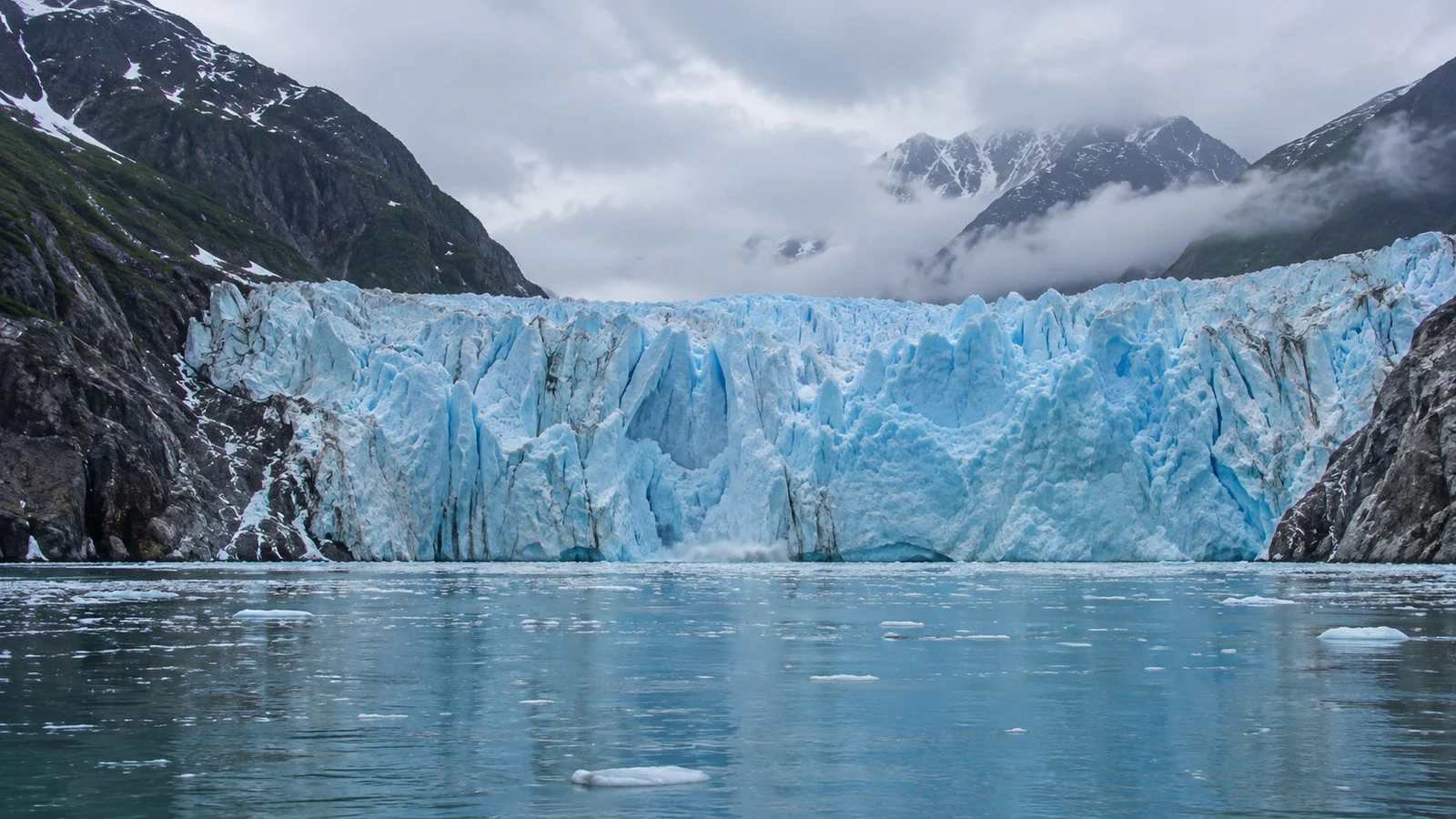 the jagged blue ice face of Dawes Glacier at the head of Endicott Arm Alaska, viewed across cold water